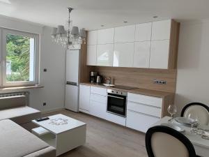 a kitchen with white cabinets and a living room at Apartment Naturjuwel in Hünxe