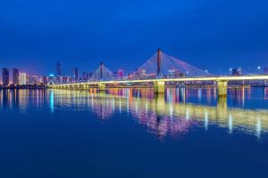 a bridge over a body of water at night at Hilton Changsha Riverside in Changsha