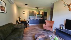 ein Wohnzimmer mit einem Sofa und einem Tisch sowie eine Küche in der Unterkunft Huisje Weideblik in Doornspijk