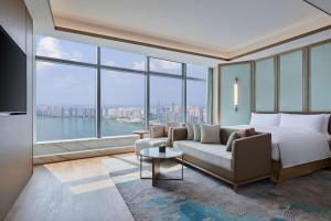 a bedroom with a bed and a couch and a large window at Hilton Changsha Riverside in Changsha