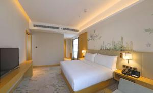 a bedroom with a white bed and a television at Hilton Garden Inn Changzhou Xinbei in Changzhou