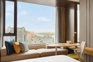 une chambre d'hôtel avec un canapé et une grande fenêtre dans l'établissement Hilton Garden Inn Dandong, à Dandong