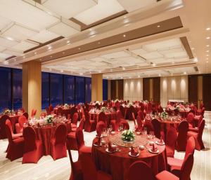 um salão de banquetes com mesas e cadeiras vermelhas em Hilton Garden Inn Dandong em Dandong
