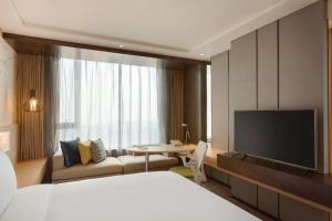 een hotelkamer met een bed en een televisie bij Hilton Garden Inn Dandong in Dandong
