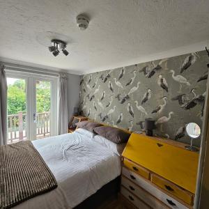 Un dormitorio con una cama y una pared con pájaros. en Goonearl Simply Stay, en Scorrier