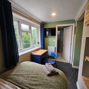 Schlafzimmer mit einem Bett, einem Schreibtisch und einem Fenster in der Unterkunft Goonearl Simply Stay in Scorrier