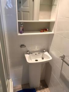 ein weißes Badezimmer mit einem Waschbecken und einem Spiegel in der Unterkunft Logie Green - beautiful and central one bed flat in Edinburgh