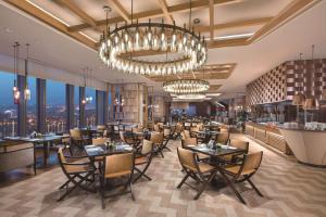 un restaurant avec des tables et des chaises et un lustre dans l'établissement Hilton Fuzhou, à Fuzhou