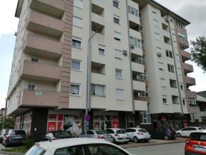 - un grand immeuble avec des voitures garées devant dans l'établissement Apartman Jana, à Doboj