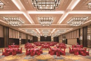 een grote feestzaal met rode tafels en stoelen bij Hilton Fuzhou in Fuzhou