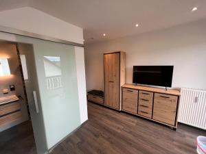 a living room with a flat screen tv on a dresser at Pension FeWo Schwärzer in Weiherhammer