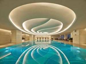 a large swimming pool with a large ceiling in a building at Hilton Dalian in Dalian