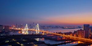 eine Brücke über einen Fluss mit einer Stadt in der Nacht in der Unterkunft Hilton Haikou in Haikou