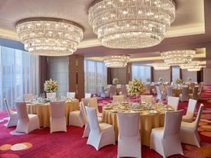 a banquet room with tables and chairs and chandeliers at Hilton Haikou in Haikou +102 photos
