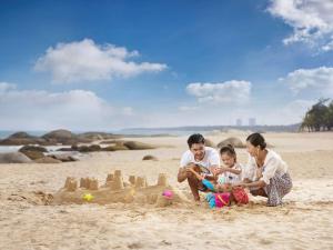 a family playing with a sand castle on the beach at Hilton Wenchang in Wenchang