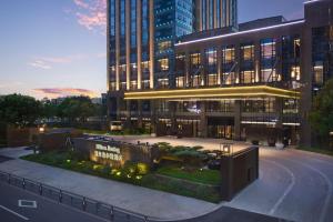 a large building in a city at night at Hilton Jiaxing in Jiaxing