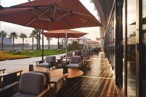 a row of tables and chairs with umbrellas on a patio at Canopy By Hilton Hangzhou Jinsha Lake in Hangzhou