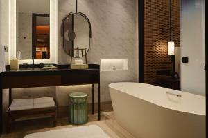 uma casa de banho com uma banheira, um lavatório e um espelho. em Canopy By Hilton Hangzhou Jinsha Lake em Hangzhou