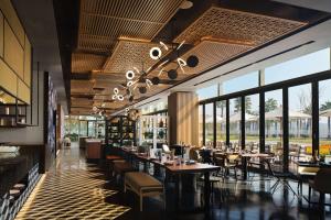 a restaurant with tables and chairs and windows at Canopy By Hilton Hangzhou Jinsha Lake in Hangzhou