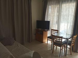 Una sala de estar con una mesa de cristal y un televisor. en Faros Beach, en Pafos