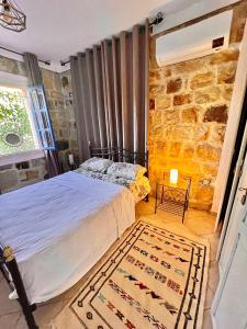 a bedroom with a bed and a stone wall at Dar Bakkali Nadi in Tangier