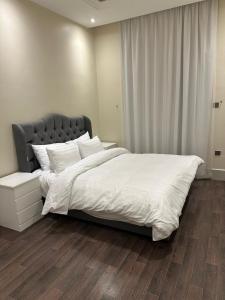 um quarto com uma cama grande e lençóis brancos em شقة نيرفانا ريزدنس Nirvana Residence Apt em Riyadh
