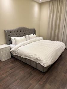 um quarto com uma cama grande e lençóis brancos em شقة نيرفانا ريزدنس Nirvana Residence Apt em Riyadh