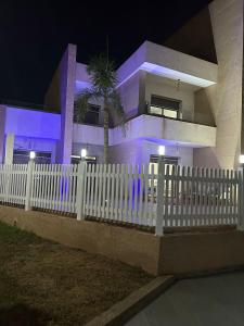 una cerca blanca frente a una casa con luces púrpuras en Marina saidia luxury Duplex pool & garden view, en Saidia 