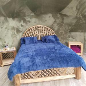 een slaapkamer met een houten bed en een blauwe deken bij glamping casa blanca in Guatavita
