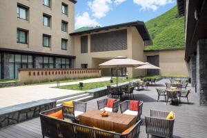 an outdoor patio with tables and chairs and an umbrella at Hilton Garden Inn Jiuzhaigou in Jiuzhaigou