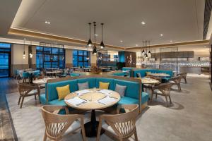 a restaurant with blue couches and tables and chairs at Hilton Garden Inn Jiuzhaigou in Jiuzhaigou