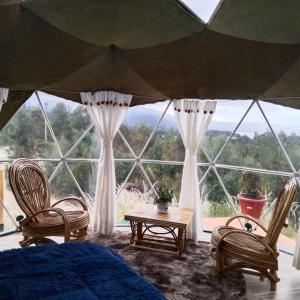 Zimmer mit 2 Stühlen, einem Tisch und einem großen Fenster in der Unterkunft glamping casa blanca in Guatavita