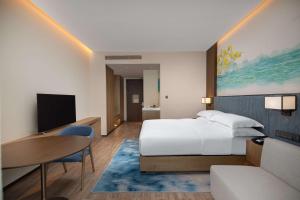 een hotelkamer met een bed en een tafel en een televisie bij Hilton Garden Inn Jiuzhaigou in Jiuzhaigou