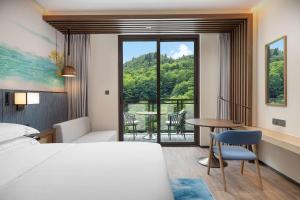 a hotel room with a bed and a table and chairs at Hilton Garden Inn Jiuzhaigou in Jiuzhaigou +47 photos