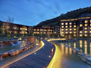 a building with a river in front of a building at Hilton Jiuzhaigou Resort in Jiuzhaigou