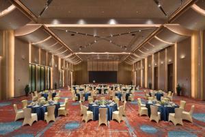 un salón de banquetes con mesas, sillas y un escenario en Hilton Jiuzhaigou Resort, en Jiuzhaigou