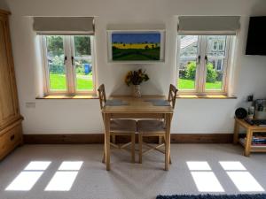 a table and chairs in a room with windows at The Dale at Greystones - Luxurious annexe with stunning view in Buckden
