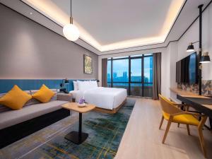 南昌市にあるHilton Garden Inn Nanchangのベッドとデスクが備わるホテルルームです。