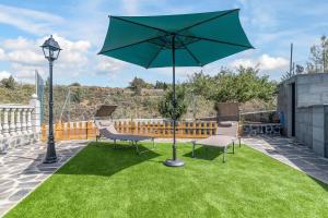 a patio with a table and a green umbrella at Raíces Vivas Vivienda Vacacional in Vega de San Mateo