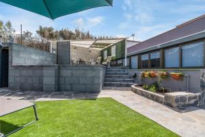 a house with a lawn and an umbrella at Raíces Vivas Vivienda Vacacional in Vega de San Mateo +34 photos