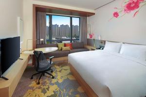 a hotel room with a bed and a living room at Hilton Garden Inn Qidong in Qidong