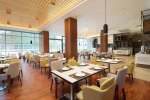 a restaurant with tables and chairs and a kitchen at Hilton Garden Inn Zhuhai Hengqin in Zhuhai