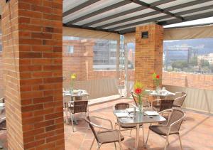 un patio con mesas y sillas y una pared de ladrillo en Apartasuites BellHouse Bogotá en Bogotá