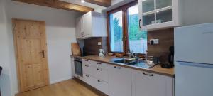 a kitchen with white cabinets and a sink and a window at Chata pod Barancom in Smrečany