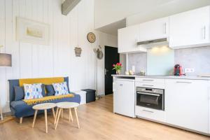 a living room with a blue couch and a kitchen at Au cœur de St Martin : La Cible in Saint-Martin-de-Ré +20 photos