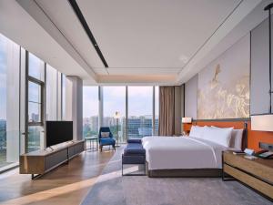pokój hotelowy z łóżkiem i telewizorem w obiekcie Hilton Guiyang w mieście Guiyang