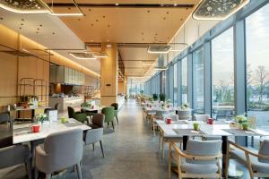 珠海市にあるHilton Garden Inn Zhuhai Hengqin Sumlodol Parkのテーブルと椅子、大きな窓のあるレストラン