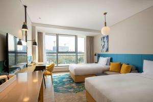 une chambre d'hôtel avec deux lits et un canapé dans l'établissement Hilton Garden Inn Zhuhai Hengqin Sumlodol Park, à Zhuhai