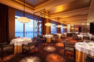 a restaurant with tables and chairs and large windows at Hilton Nanjing Riverside in Nanjing