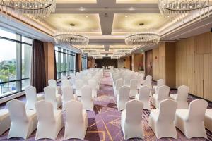 une salle de conférence avec des chaises blanches et des lustres dans l'établissement Hilton Garden Inn Shanghai Hongqiao NECC, à Shanghai